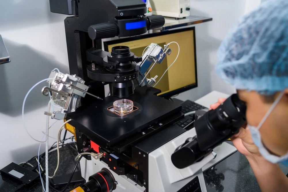 Doctor using IVF micromanipulator with Petri Dish on it for insemination of the egg in the laboratory of the in vitro fertilization